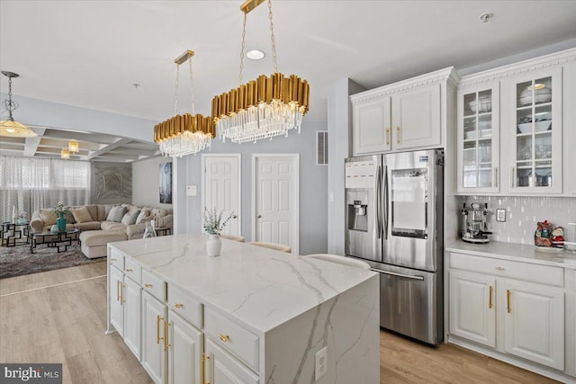 kitchen with stainless steel fridge, a kitchen island, white cabinetry, and light hardwood / wood-style flooring