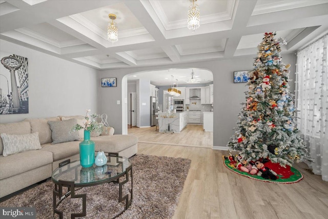 living room featuring beamed ceiling, ornamental molding, light hardwood / wood-style floors, and coffered ceiling