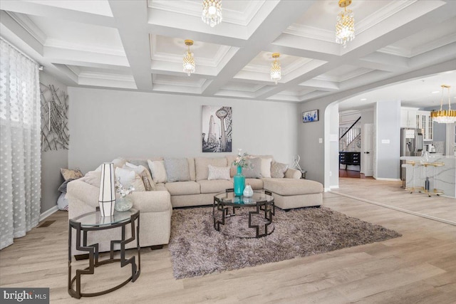 living room with coffered ceiling, light wood-type flooring, crown molding, and an inviting chandelier