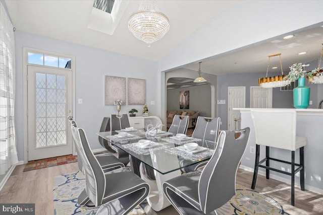 dining space with light hardwood / wood-style flooring, vaulted ceiling, and a notable chandelier