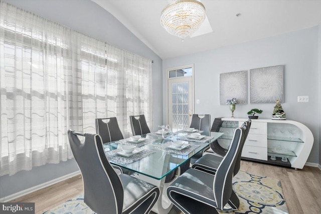 dining space featuring a chandelier, light hardwood / wood-style floors, and vaulted ceiling