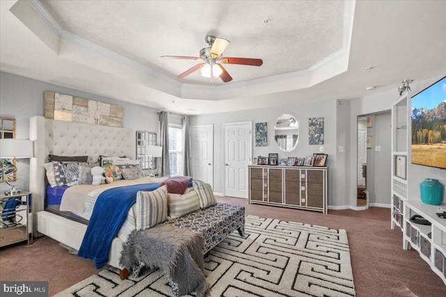 bedroom with carpet flooring, ornamental molding, a raised ceiling, ceiling fan, and multiple closets