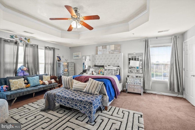 carpeted bedroom with ceiling fan, crown molding, and a tray ceiling