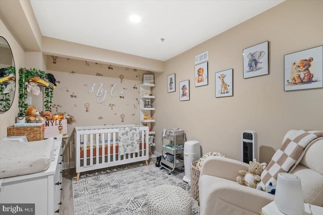 bedroom with light hardwood / wood-style floors and a nursery area