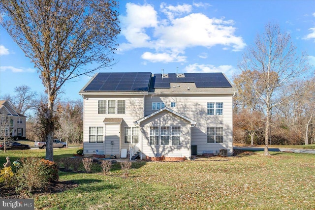 rear view of property with solar panels and a lawn