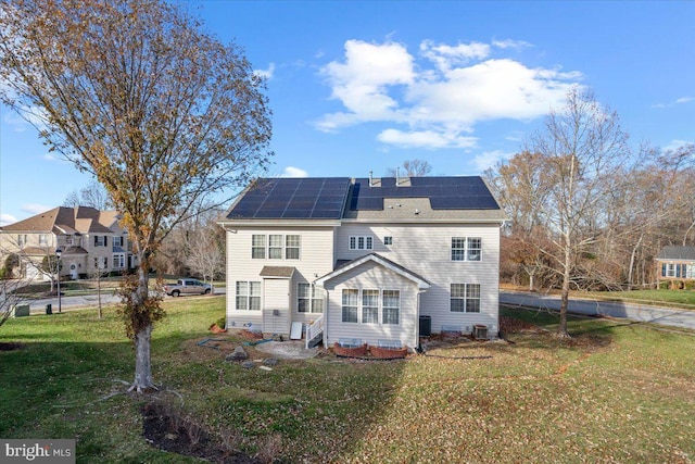 back of house with a yard and solar panels