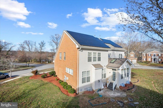 view of side of home with solar panels and a yard