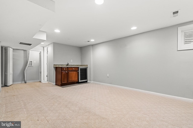 basement featuring light carpet, indoor bar, and wine cooler