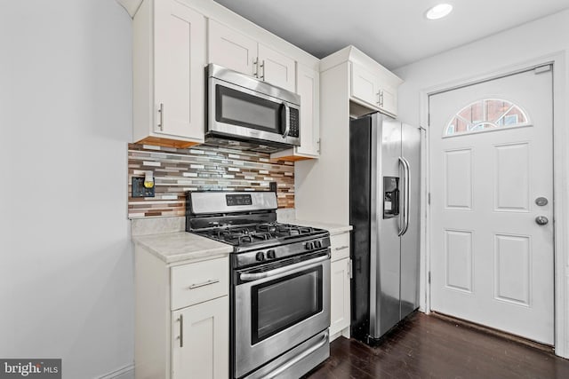 kitchen with white cabinets, appliances with stainless steel finishes, dark hardwood / wood-style flooring, and tasteful backsplash