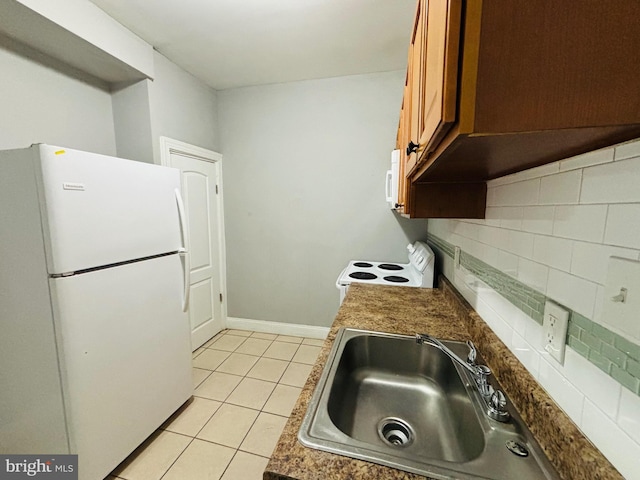 kitchen featuring tasteful backsplash, sink, light tile patterned floors, and white appliances