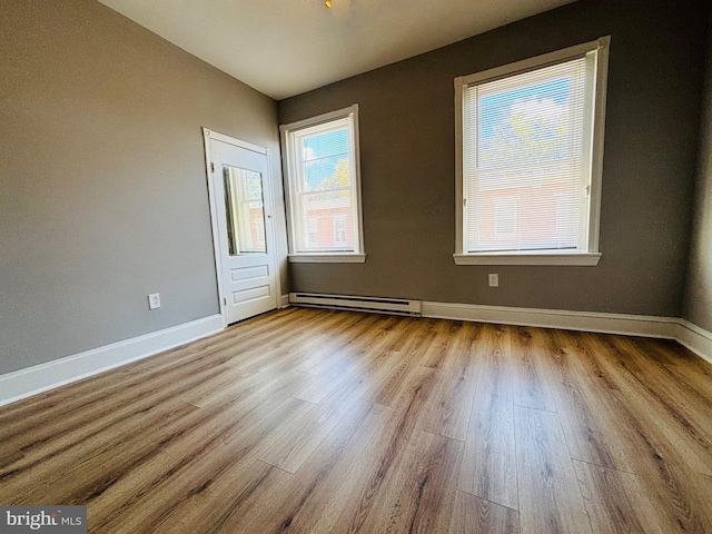 empty room with light hardwood / wood-style flooring and a baseboard radiator