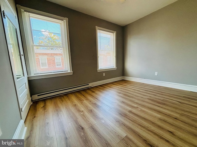 unfurnished room featuring baseboard heating and light hardwood / wood-style floors