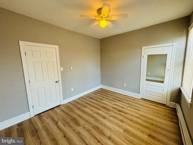 unfurnished bedroom featuring ceiling fan, a baseboard radiator, and light hardwood / wood-style floors