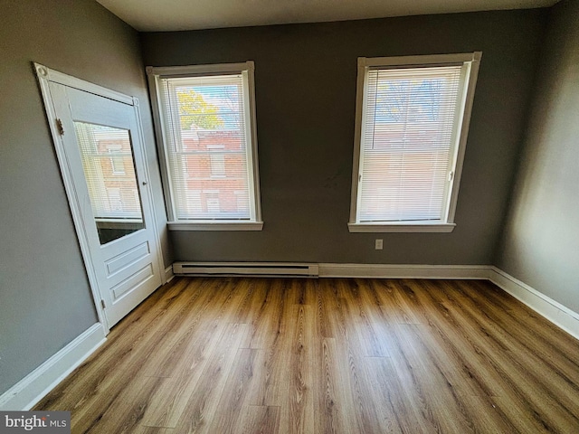 unfurnished room featuring light hardwood / wood-style floors and a baseboard heating unit