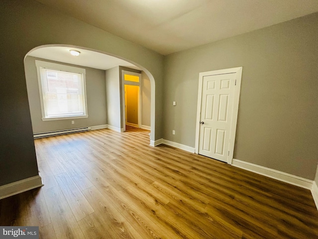 unfurnished room with hardwood / wood-style floors and baseboard heating