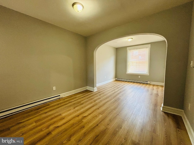 empty room with hardwood / wood-style flooring and a baseboard heating unit