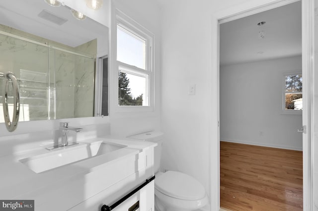 bathroom with hardwood / wood-style floors, vanity, toilet, and walk in shower