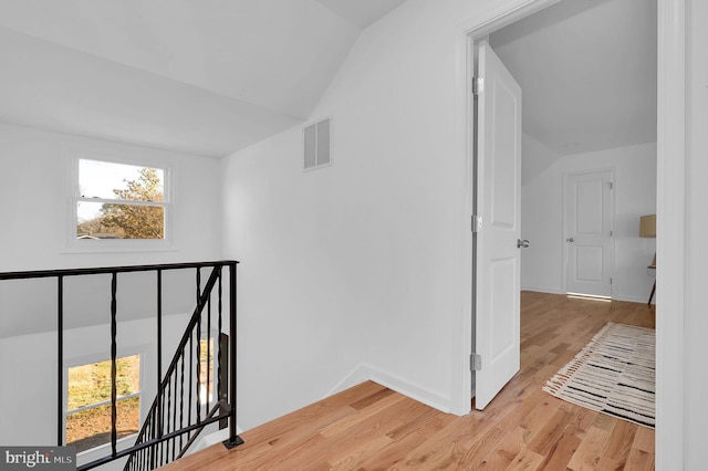 hall featuring light hardwood / wood-style floors and vaulted ceiling