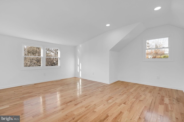 additional living space featuring lofted ceiling, a healthy amount of sunlight, and light hardwood / wood-style floors