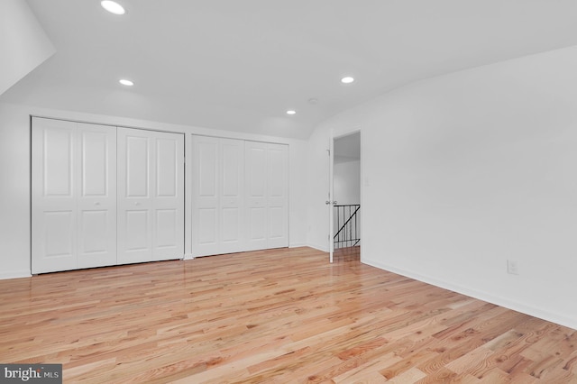 unfurnished bedroom with light hardwood / wood-style floors and multiple closets