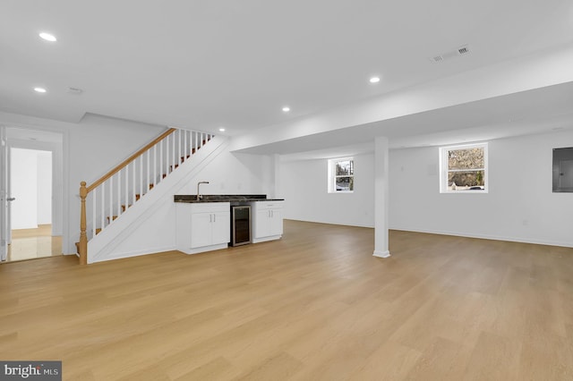 interior space with wine cooler, light wood-type flooring, and wet bar