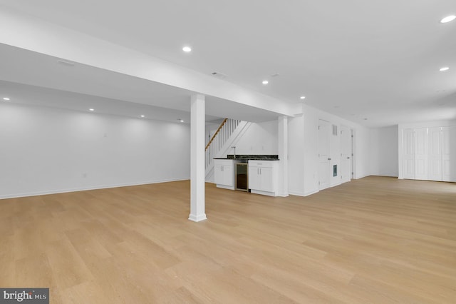 basement featuring light hardwood / wood-style flooring and beverage cooler