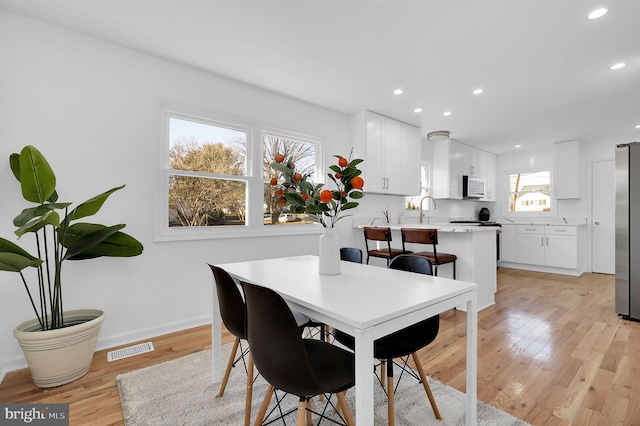 dining area featuring light hardwood / wood-style floors, sink, and a wealth of natural light