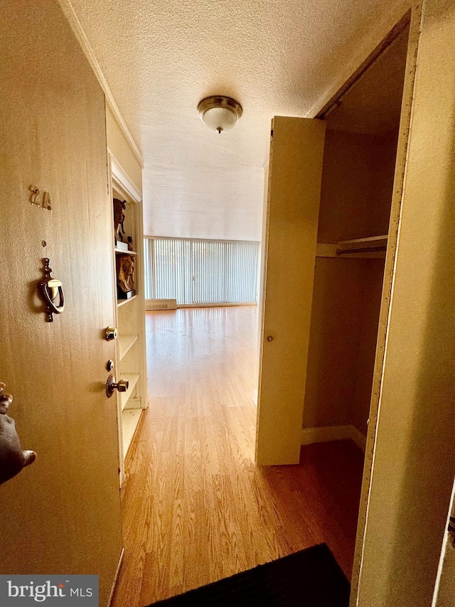 corridor with a textured ceiling and hardwood / wood-style flooring