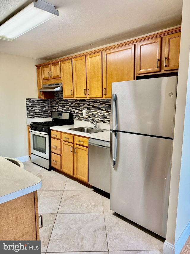 kitchen featuring sink, light tile patterned floors, appliances with stainless steel finishes, tasteful backsplash, and extractor fan