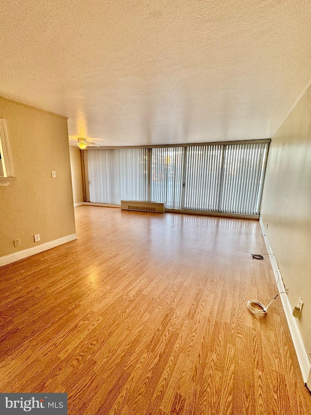 unfurnished room featuring light hardwood / wood-style floors and a textured ceiling