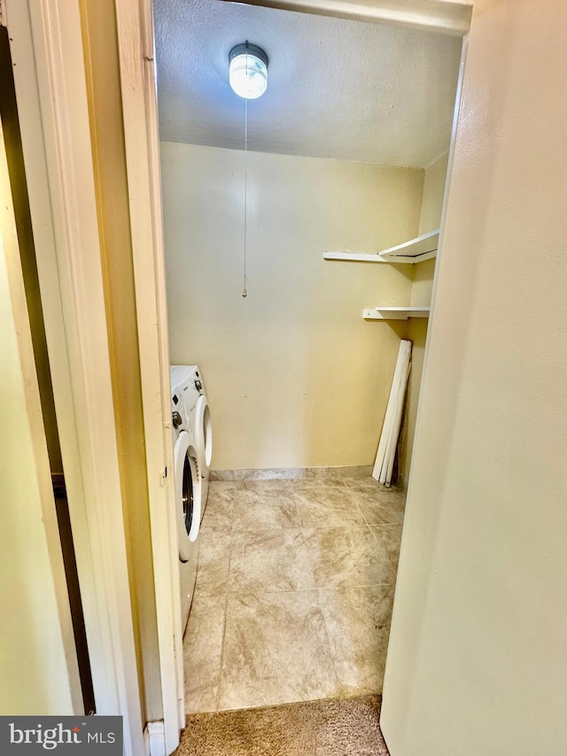 laundry area featuring carpet flooring, a textured ceiling, and washing machine and clothes dryer