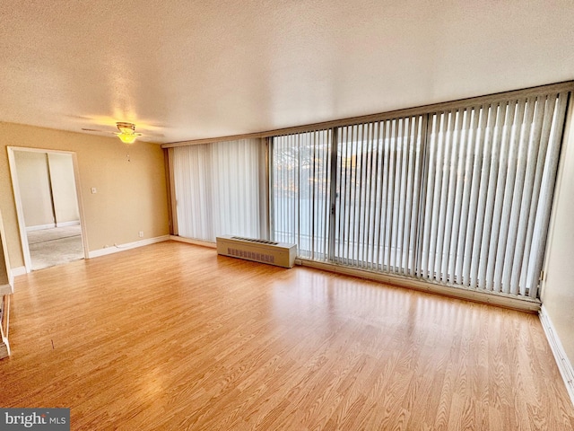 unfurnished living room with hardwood / wood-style floors, ceiling fan, radiator heating unit, and a textured ceiling