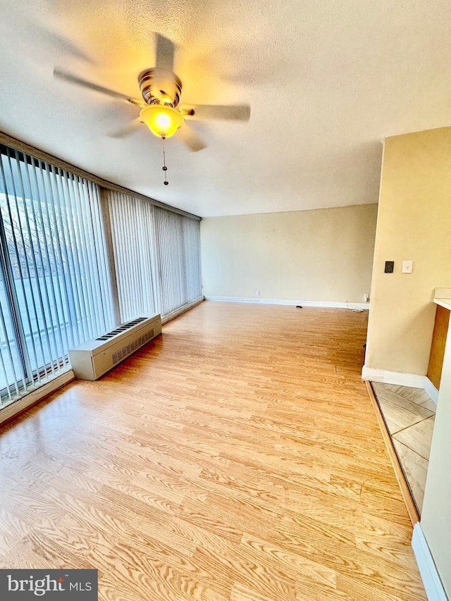 empty room with ceiling fan, a textured ceiling, and light wood-type flooring