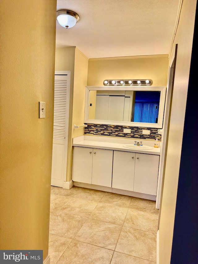 bathroom with tile patterned floors, decorative backsplash, vanity, and ornamental molding