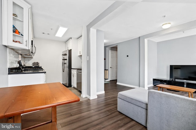 kitchen with backsplash, white cabinetry, stainless steel appliances, and dark wood-type flooring