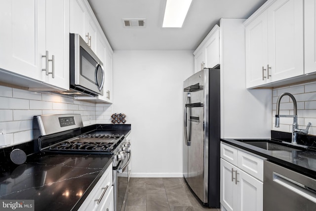 kitchen featuring dark stone countertops, white cabinetry, sink, and stainless steel appliances