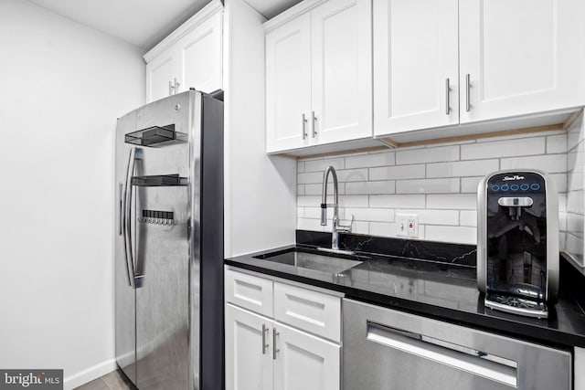 kitchen with white cabinets, sink, dark stone countertops, appliances with stainless steel finishes, and tasteful backsplash