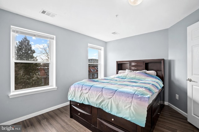 bedroom with dark hardwood / wood-style floors and multiple windows