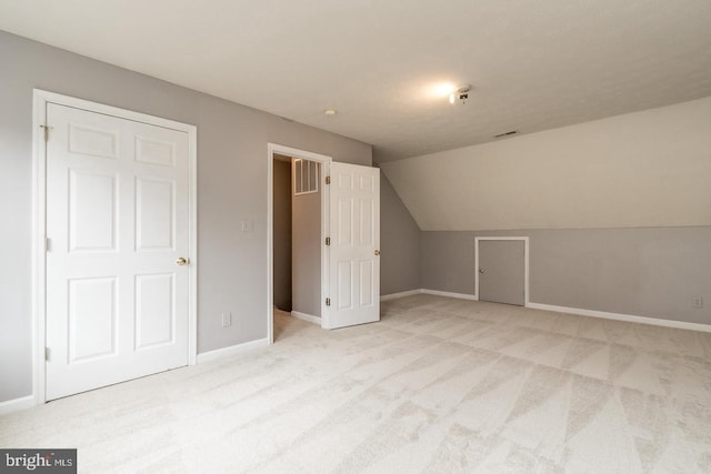 additional living space with light colored carpet and vaulted ceiling