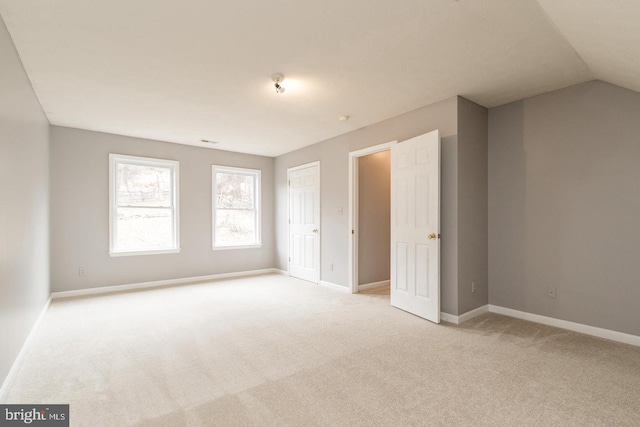 interior space featuring light colored carpet, vaulted ceiling, and a closet