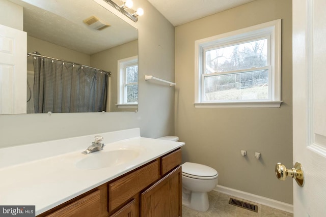 bathroom with tile patterned floors, plenty of natural light, vanity, and toilet