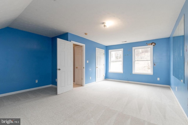 unfurnished bedroom featuring light carpet and lofted ceiling