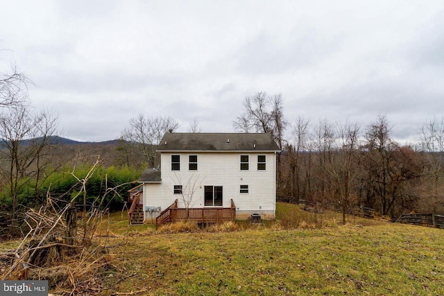 back of property with a deck and a yard