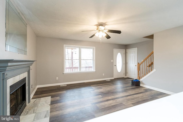 entrance foyer featuring a fireplace, a textured ceiling, ceiling fan, and dark wood-type flooring