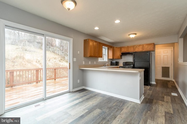 kitchen featuring kitchen peninsula, dark wood-type flooring, black appliances, and sink