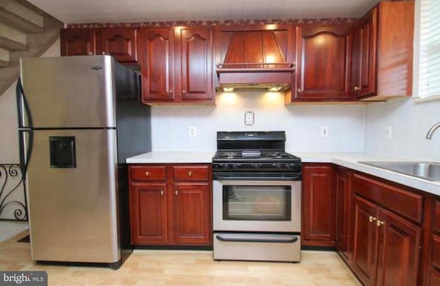 kitchen with custom exhaust hood, sink, and stainless steel appliances