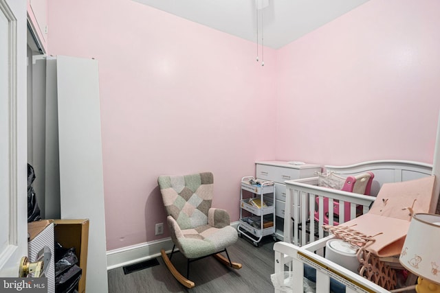 bedroom featuring dark hardwood / wood-style flooring and a crib