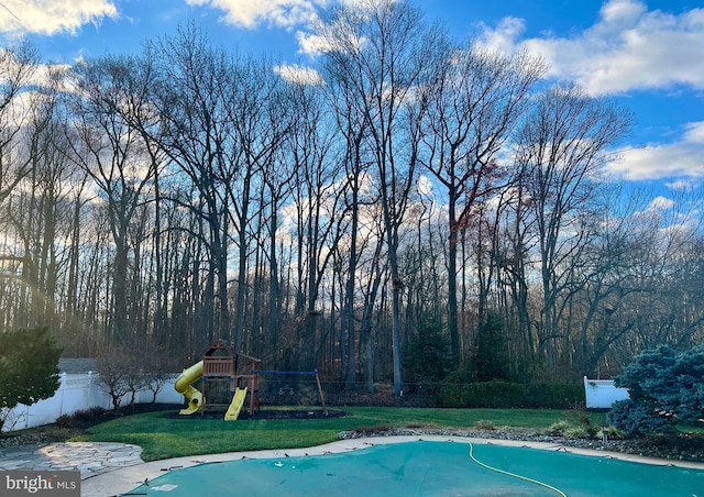 view of pool with a lawn and a playground