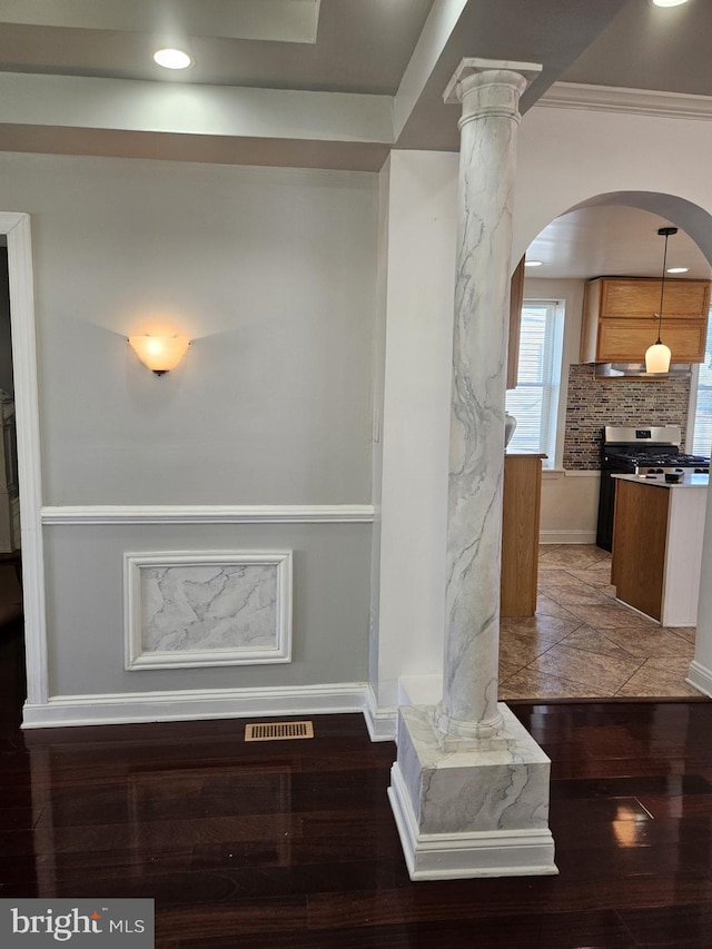 interior details featuring pendant lighting, crown molding, hardwood / wood-style flooring, stainless steel gas stove, and decorative columns