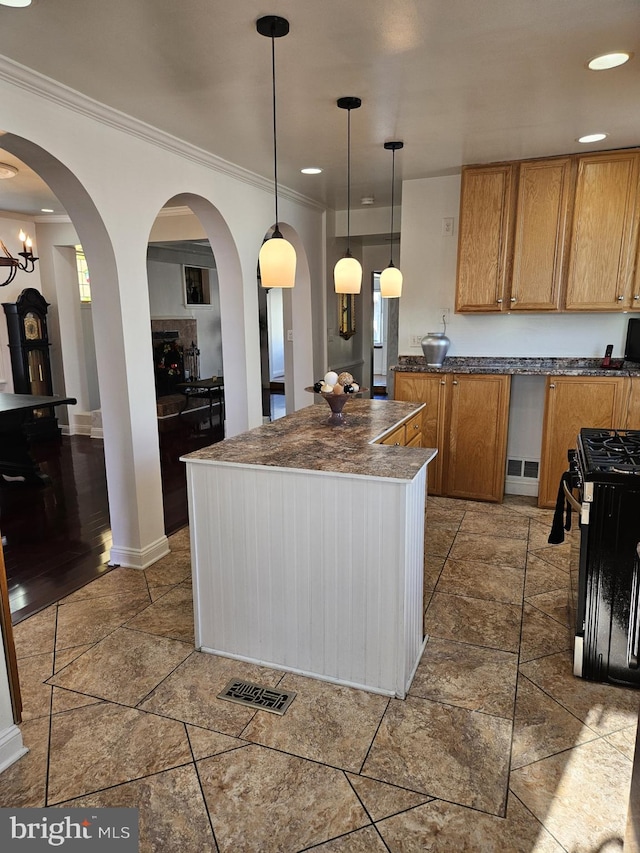 kitchen featuring a center island, ornamental molding, black gas range oven, decorative light fixtures, and a chandelier